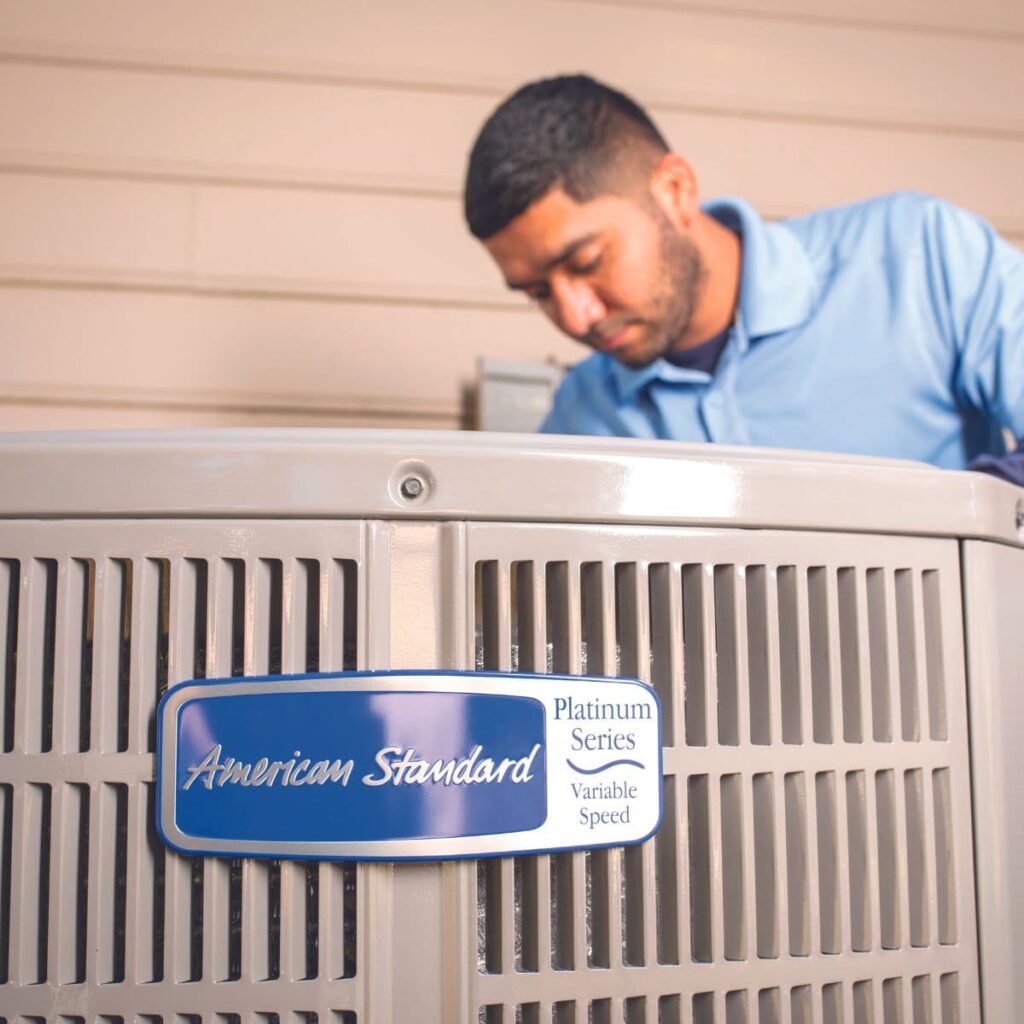 american standard technician performing repairs on outdoor hvac unit