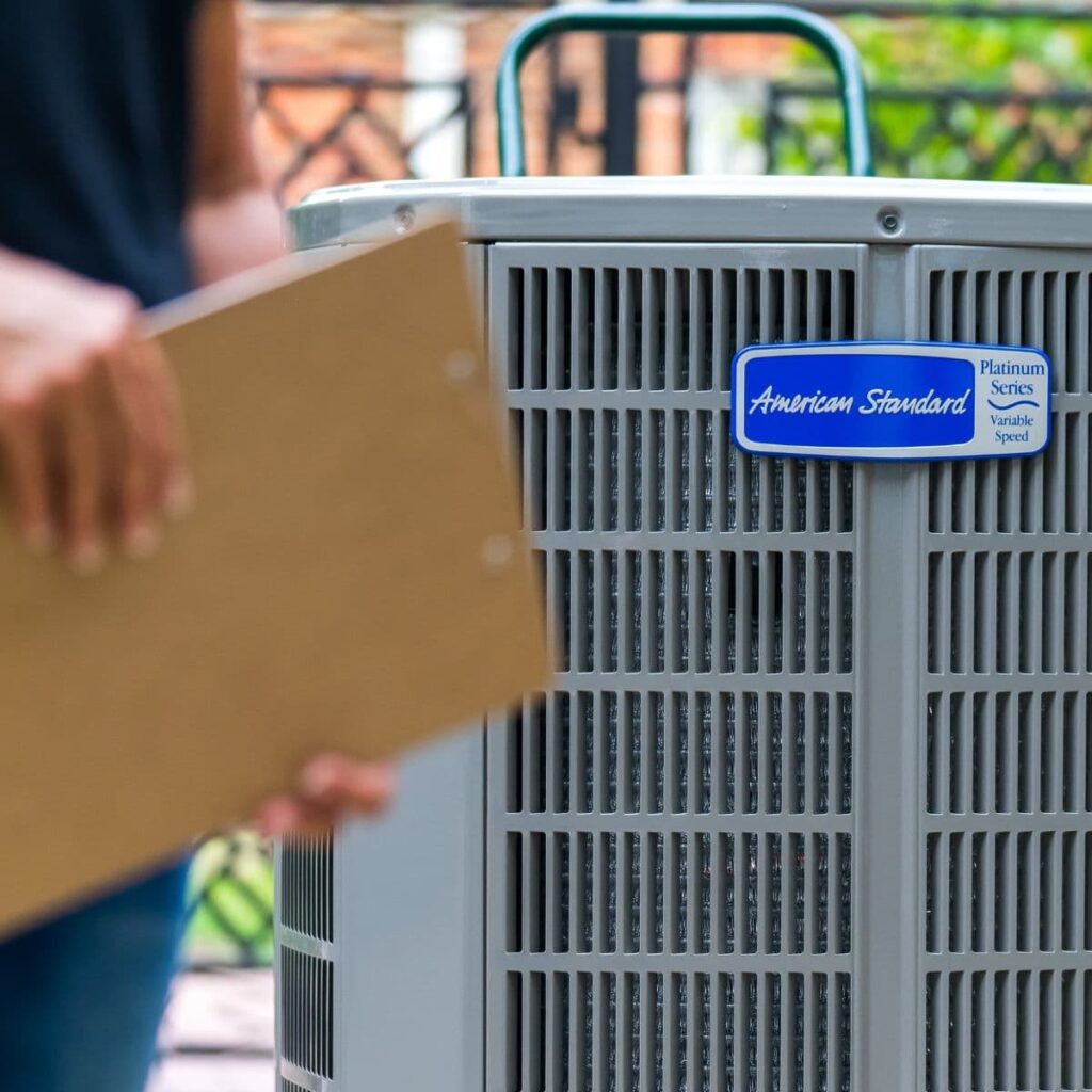 closeup of outdoor hvac unit with a blurry look at a technician holding a clipboard in front of the system