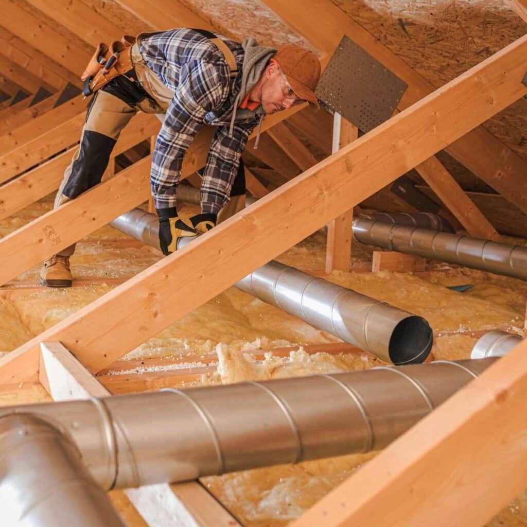 air duct tubes being installed in the attic by hvac technician