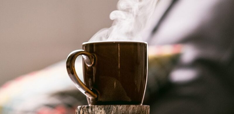 closeup of a brown cup of warm steaming coffee