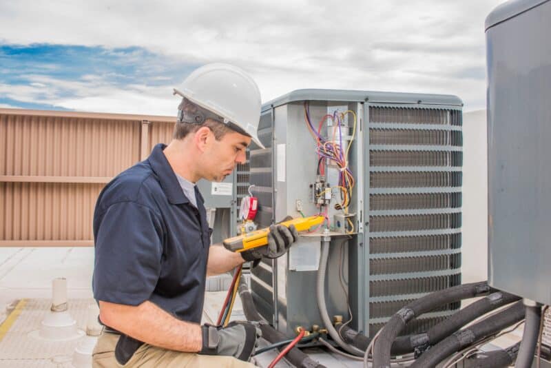 hvac technician performing repairs on an outdoor hvac unit