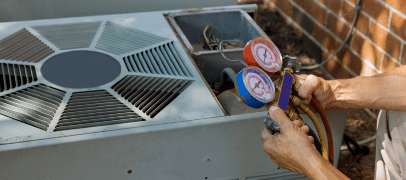 closeup of a technician reading pressure with a tool on an outdoor air conditioning unit